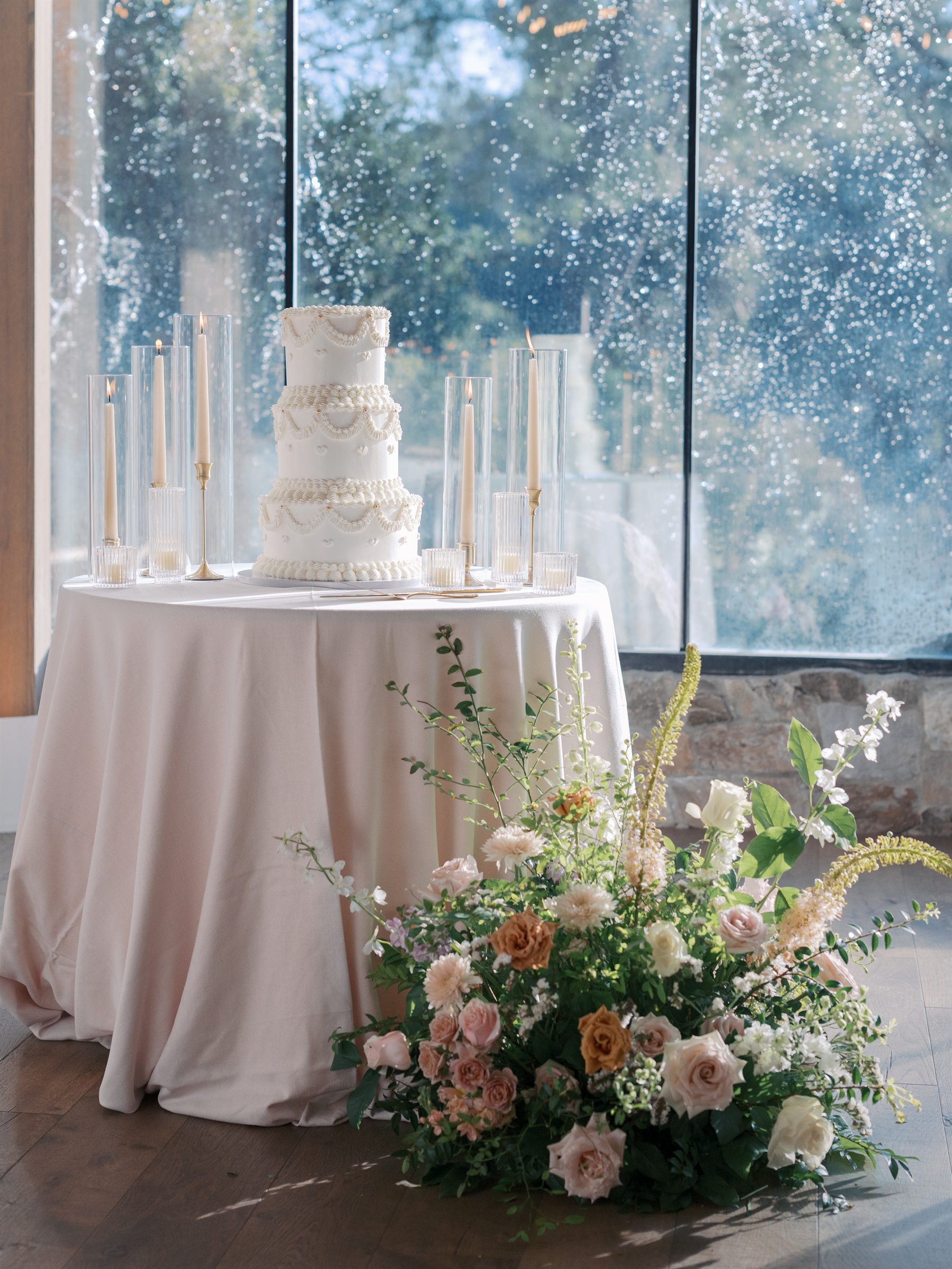 Tiered wedding cake displayed beneath a dramatic floral installation