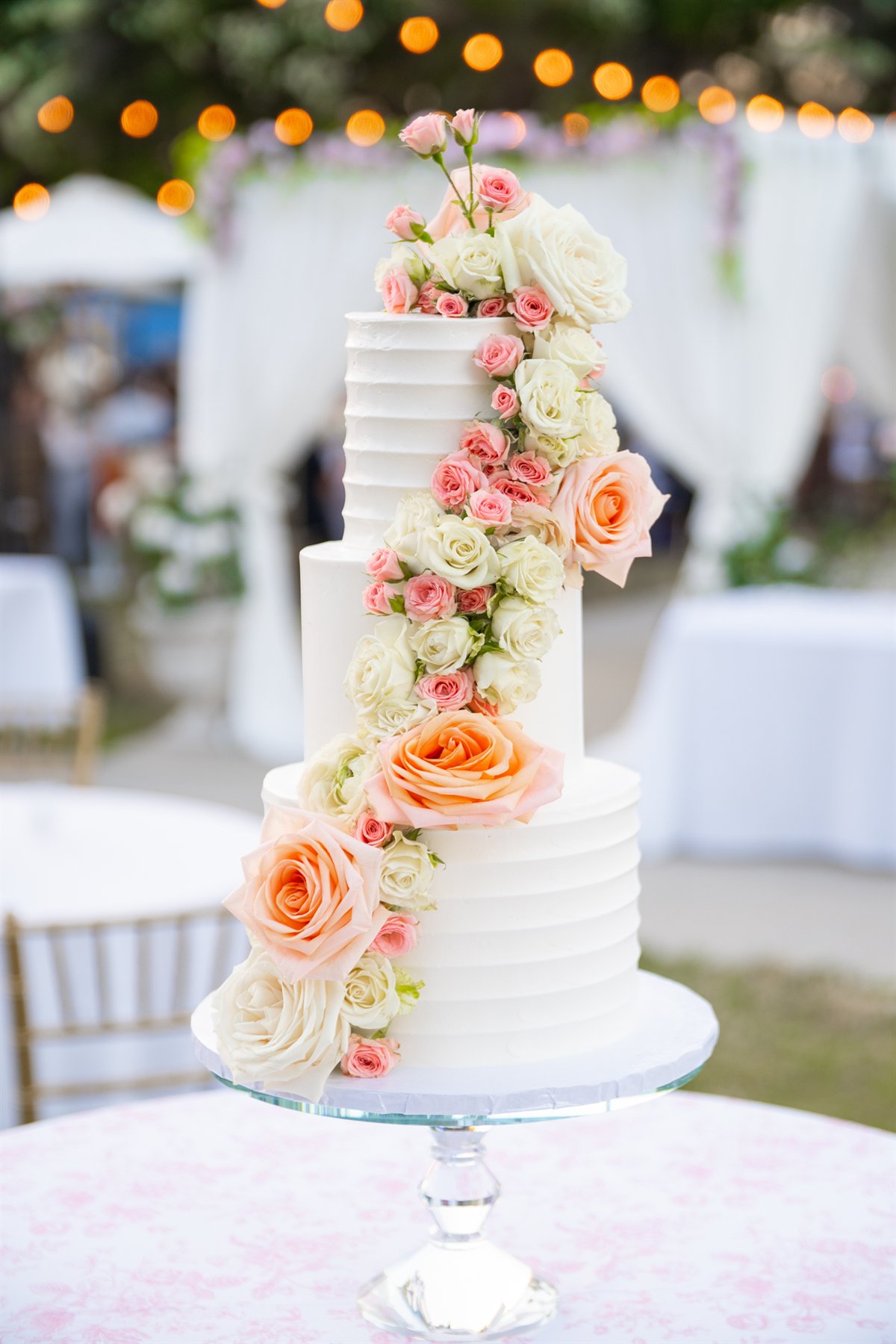 Three-tier wedding cake cascading with blush and ivory roses at Calamigos Ranch